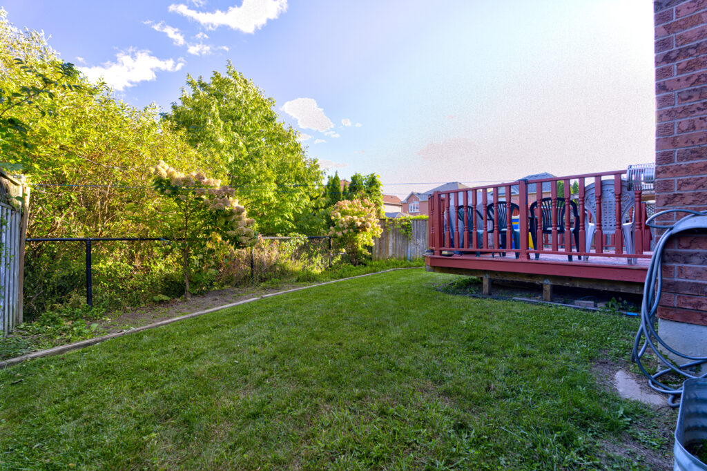 Backyard deck and walkway behind brick house